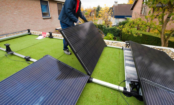 worker installing solar panel on roof